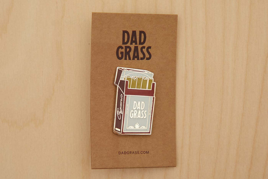 Dad Grass Pack Pin on cardboard on a wooden table